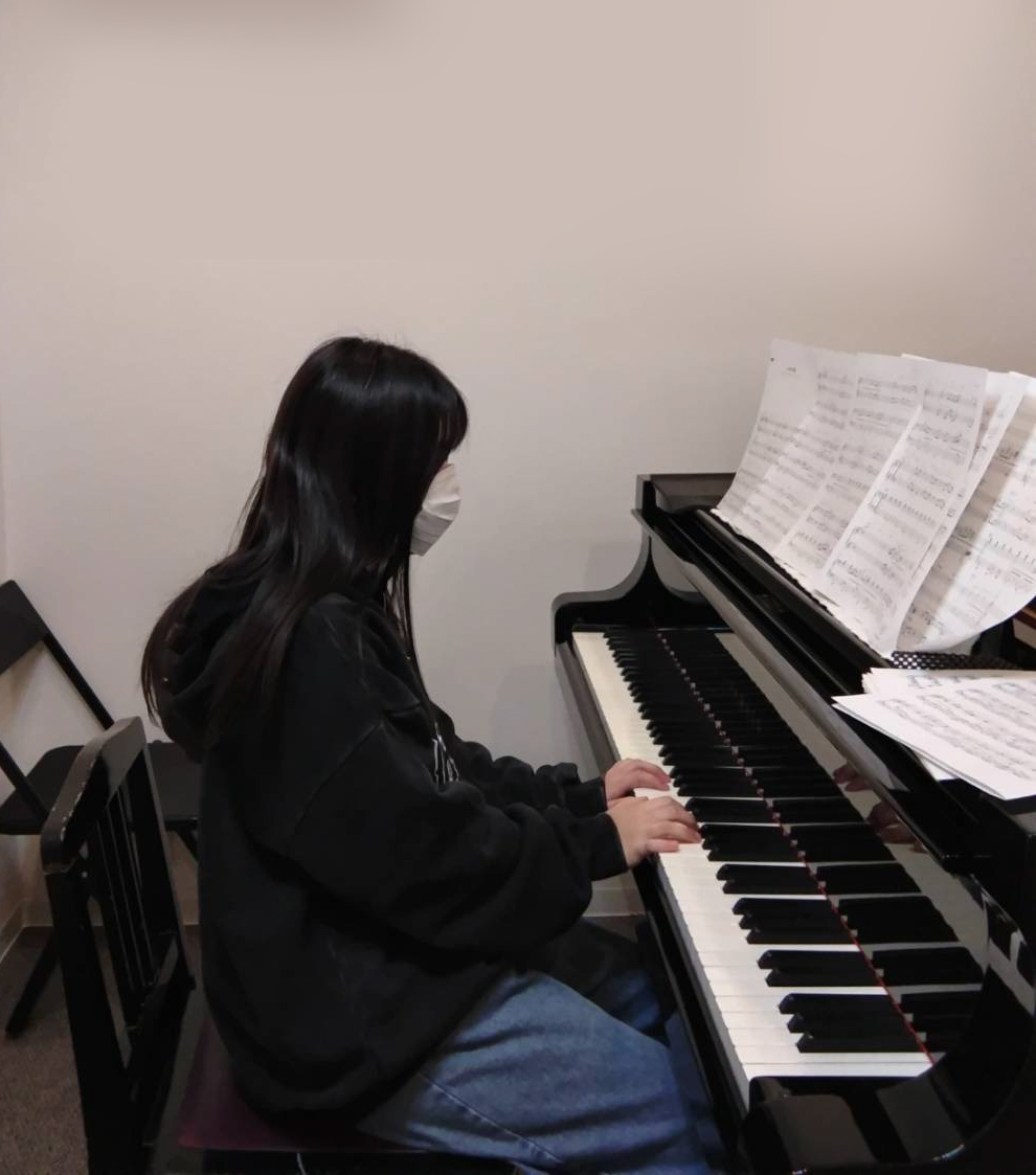 経験のある生徒がグランドピアノで楽譜を見ながら演奏している様子